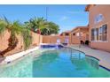 Sparkling swimming pool with baja step, spa, and lounge chairs next to lush palm trees and patio at 7908 W Harmony Ln, Peoria, AZ 85382