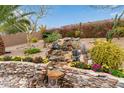 Scenic backyard featuring a tiered rock waterfall and vibrant desert flora, perfect for relaxation at 10796 E Betony Dr, Scottsdale, AZ 85255