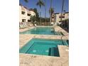 A community pool with a hot tub is surrounded by lounge chairs on a sunny day at 12123 W Bell Rd # 118, Surprise, AZ 85378