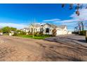 Exterior view with lush landscaping showing manicured lawn, brick driveway, and attached garages on a sunny day at 20690 E Sunset Dr, Queen Creek, AZ 85142
