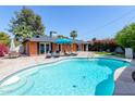 Sparkling pool with lounge chairs in a backyard with a brick house and mature landscaping under a clear blue sky at 3514 N 83Rd St, Scottsdale, AZ 85251