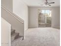 Neutral living room featuring a staircase, plush carpeting, and a sliding glass door to the backyard at 5472 W Fulton St, Phoenix, AZ 85043
