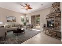 Comfortable living room with a cozy stone fireplace and sliding glass doors to the outdoor space at 8367 W Lariat Ln, Peoria, AZ 85383