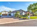 View of the home's exterior and three-car garage with a brick-paved driveway at 10059 W Villa Lindo Dr, Peoria, AZ 85383