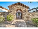 Close up of the stone gatehouse with iron gate and lush landscaping at 10059 W Villa Lindo Dr, Peoria, AZ 85383