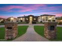 Elegant single-story home featuring a circular driveway and striking entry pillars at dusk at 19717 E Country Meadows Dr, Queen Creek, AZ 85142