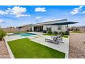 A modern backyard featuring a sparkling pool, artificial turf, and comfortable lounge seating with an umbrella at 22372 E Duncan St, Queen Creek, AZ 85142