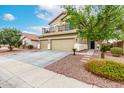 Home featuring a balcony above the three-car garage, low maintenance landscaping, and inviting entry at 25695 W Crown King Rd, Buckeye, AZ 85326