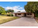 Charming single-story home featuring mature landscaping, a covered carport, and a lengthy driveway at 4249 E Mitchell Dr, Phoenix, AZ 85018