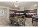 Large kitchen with dining space, modern chandelier, dark cabinets, granite countertops, and stainless steel appliances at 5917 N 133Rd Ave, Litchfield Park, AZ 85340