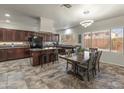 Bright kitchen with dark wood cabinets, granite counters, island, and dining area with modern chandelier at 5917 N 133Rd Ave, Litchfield Park, AZ 85340