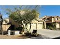 View of a two-story home with a three-car garage, partially obscured by a tree at 7511 S 45Th Dr, Laveen, AZ 85339