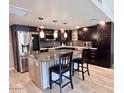 Contemporary kitchen features dark wood cabinets, stainless steel appliances, and a center island with seating at 7920 E Camelback Rd # 203, Scottsdale, AZ 85251