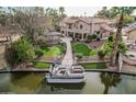 Beautiful waterfront home featuring a private dock, boat, lush landscaping, and manicured lawn at 11101 W Sieno Pl, Avondale, AZ 85392