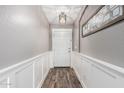 Bright hallway with white wainscoting, wood-look floors, and stylish light fixture at 3423 E Crescent Way, Gilbert, AZ 85298