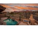 Inviting backyard pool with desert landscaping, outdoor fireplace, and mountain views at 4413 S Tigre Del Mar Dr, Gold Canyon, AZ 85118