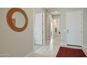 Bright hallway featuring tile flooring, a decorative mirror, and white paneled doors at 5195 N 207Th Dr, Buckeye, AZ 85396