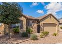 Charming home with neutral tones, a stone accent wall, desert landscaping, and an attached garage at 520 S 196Th Dr, Buckeye, AZ 85326