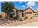 Charming home with neutral tones, a stone accent wall, desert landscaping, and an attached garage at 520 S 196Th Dr, Buckeye, AZ 85326
