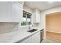 Bright kitchen featuring white cabinets, a stainless steel sink, modern countertops, and a large window for natural light at 13611 N 98Th Ave # D, Sun City, AZ 85351