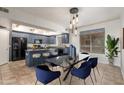 Modern dining area featuring blue cabinetry, glass table, unique light fixture, and tile flooring at 16825 N 14Th St # 125, Phoenix, AZ 85022