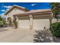 Beige two-car garage with a tile roof, set in desert landscaping with a lovely rose bush and shade tree at 2535 N Pinnule Cir, Mesa, AZ 85215