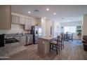 Open-concept kitchen with stainless appliances, a kitchen island with barstool seating, and gray cabinets at 2583 N Kenna Pl, Casa Grande, AZ 85122