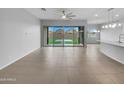 Spacious open-concept living room area with neutral paint, tile floors, and sliding glass doors at 41285 W Sussex Dr, Maricopa, AZ 85138