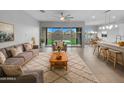 Open-concept living room with sliding glass doors and bright, neutral decor leads to the kitchen at 41285 W Sussex Dr, Maricopa, AZ 85138