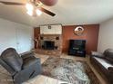 Cozy living room with a brick fireplace, ceiling fan, and comfortable seating arrangement on tile flooring at 2151 S Calle Del Marcos --, Casa Grande, AZ 85194