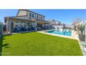 A backyard with a covered patio, a pool, a well-kept lawn and outdoor furniture at 22752 E Arroyo Verde Dr, Queen Creek, AZ 85142