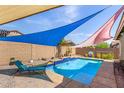 Backyard pool with sun shades, waterfall feature, and desert landscaping at 10932 E Bella Via --, Mesa, AZ 85212