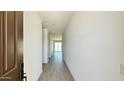 Bright hallway with tile flooring, leading towards a sunlit room with sliding glass doors at 15784 W Beryl Ave, Waddell, AZ 85355