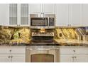 Close up of stainless steel oven and microwave with custom backsplash and white cabinets at 1701 E Colter St # 311, Phoenix, AZ 85016