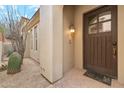 Welcoming front entry with a dark wood door, stylish light fixture, and desert landscaping at 28990 N White Feather E Ln # 182, Scottsdale, AZ 85262
