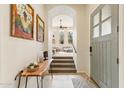 Bright foyer with tiled flooring, a wooden console table, and an open staircase leading to the living area at 28990 N White Feather E Ln # 182, Scottsdale, AZ 85262