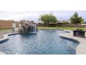 Backyard pool featuring a rock waterfall, spacious patio and view of the green grass at 30419 N Plantation Dr, San Tan Valley, AZ 85143