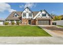 Charming Tudor-style home featuring a well-manicured lawn, brick accents, and a two-car garage at 902 W Claremont St, Phoenix, AZ 85013