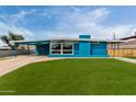 Bright blue home featuring a carport, large picture window, and a lush green lawn at 1340 E Golden Ln, Phoenix, AZ 85020