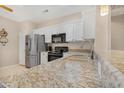Close-up of kitchen featuring granite countertops, stainless steel refrigerator, and sleek black appliances at 18668 N Lariat Ct, Surprise, AZ 85387