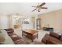 Inviting living room features tile floors, a ceiling fan, and an open layout to the kitchen and dining area at 18668 N Lariat Ct, Surprise, AZ 85387