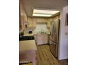 Functional kitchen with stainless steel appliances, light wood cabinetry, and laminate flooring at 311 E Lancaster Ct, Florence, AZ 85132