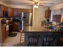 A kitchen featuring stainless steel appliances, brown cabinetry, and an island with bar seating at 5684 S 237Th Dr, Buckeye, AZ 85326