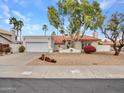 Charming single-story home featuring a landscaped front yard, tile roof, and attached two-car garage at 6704 W Topeka Dr, Glendale, AZ 85308