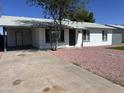 Street view of single-story home with white exterior, covered parking, and low maintenance rock landscaping at 7426 W Beryl Ave, Peoria, AZ 85345