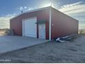 The red metal exterior of the industrial building featuring a single roll up door and a walk-in entrance at 9600 S 393Rd Ave, Tonopah, AZ 85354