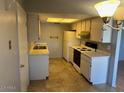 Functional kitchen with a white refrigerator, tile flooring, range and ample cabinet space for storage at 9638 W Cinnabar Ave # B, Peoria, AZ 85345