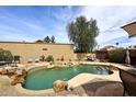 Backyard oasis with a beautiful pool, rock waterfall, desert landscaping, and lounge area at 16857 E Deuce Ct, Fountain Hills, AZ 85268