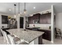 Modern kitchen featuring dark wood cabinets, stainless steel appliances, and granite countertops at 17454 W Red Fox Rd, Surprise, AZ 85387