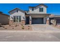 Charming two-story home with a gray stucco exterior, brick accents, and a paved driveway at 21430 W Meadowbrook Ave, Buckeye, AZ 85396
